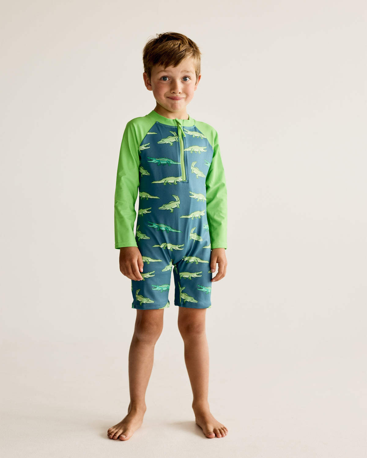 Crocodiles and Alligators print on dark green long-sleeve kids swimwear onesie, one-piece with UPF50+ sun protection and nylon fabric.