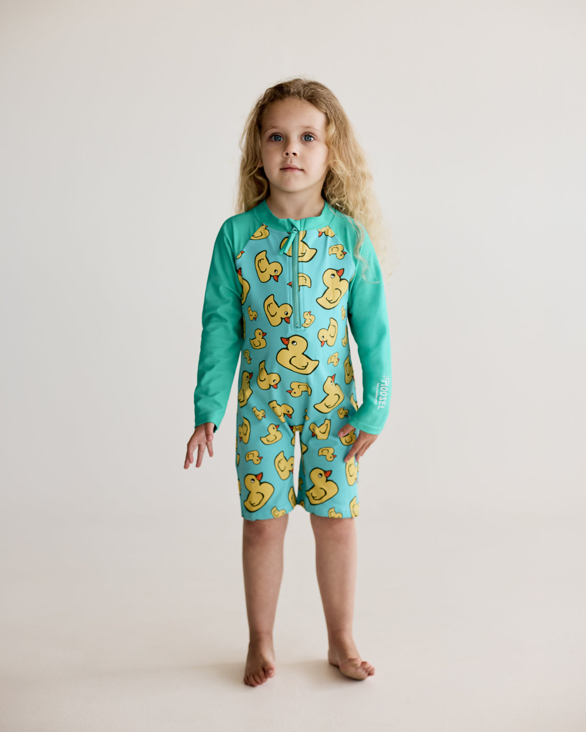 Yellow rubber ducks print on teal blue green long-sleeve kids swimwear onesie, one-piece with UPF50+ sun protection and nylon fabric.