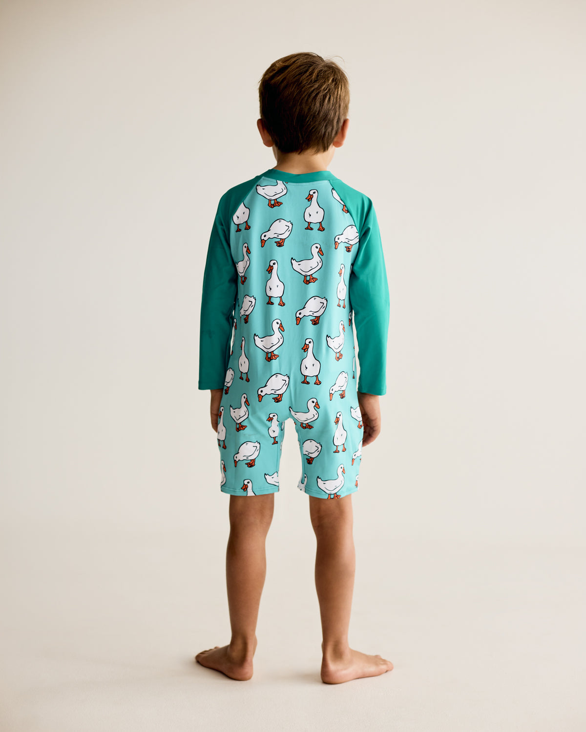 Ducks, Geese, and water bird print on teal blue green long-sleeve kids swimwear onesie, one-piece with UPF50+ sun protection and nylon fabric.