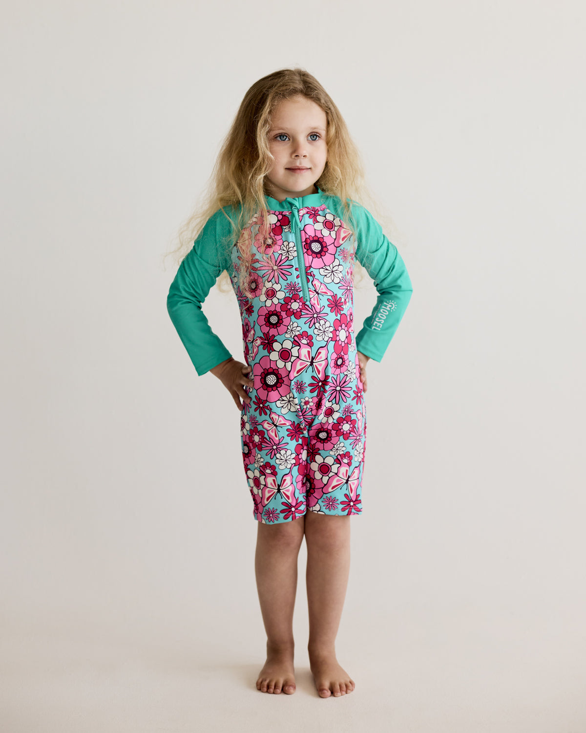 Pink White Floral, Flowers and Butterflies print on teal long-sleeve kids swimwear onesie, one-piece with UPF50+ sun protection and nylon fabric.